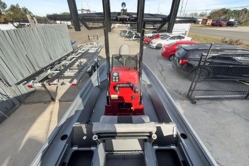 Slide: The Image of 2026 Excel Bay Pro Elite 220 boat with red console, parked near trailers and vehicles. - 6