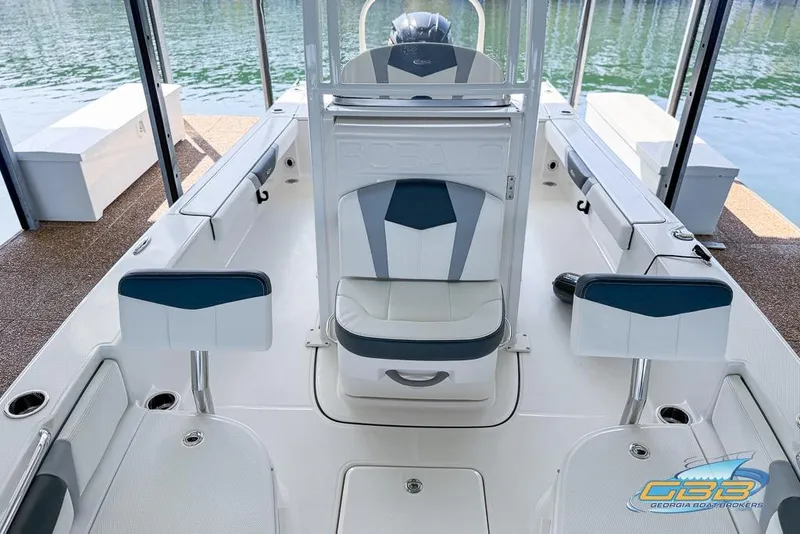 Slide: The Image of 2023 Robalo 226 Cayman boat interior with seating and console, docked by the water. - 11