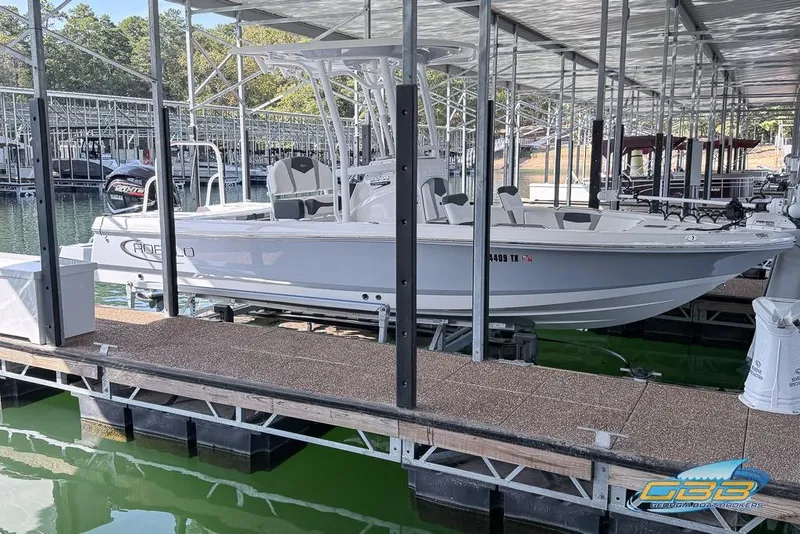 Slide: The Image of 2023 Robalo 226 Cayman boat docked in a marina under a covered structure. - 2