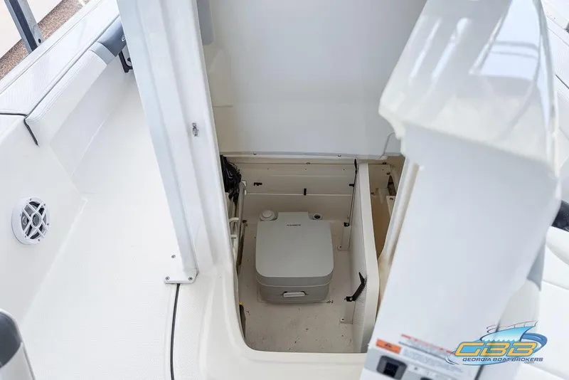 Slide: The Image of 2023 Robalo 226 Cayman boat interior with storage compartment and portable toilet. - 36