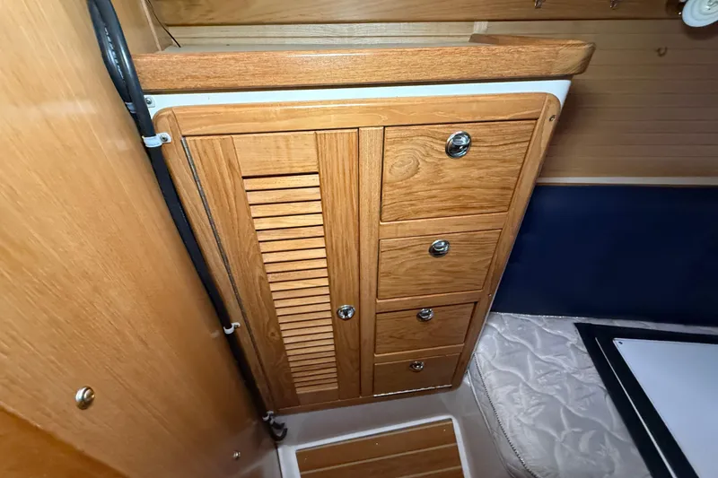 Slide: The Image of Wooden cabinetry inside a 2006 Catalina 36 MkII sailboat, featuring drawers and a louvered door. - 69