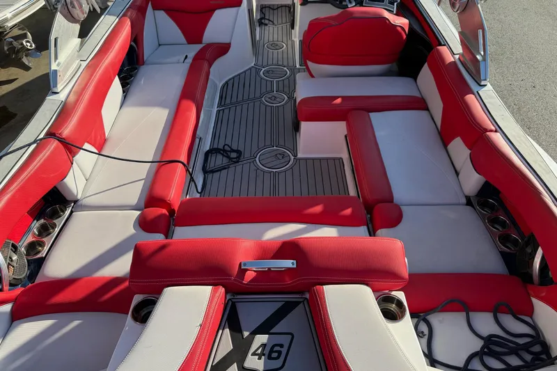 Slide: The Image of 2018 MasterCraft X46 boat interior with red and white seating, cup holders, and deck flooring. - 3