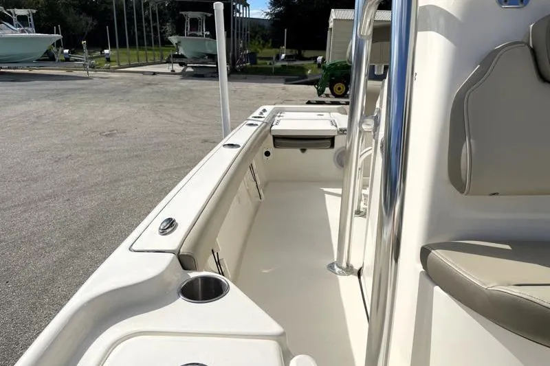 Slide: The Image of 2024 Key West 210 Bay Reef boat interior with seating and cup holders, docked near a warehouse. - 29