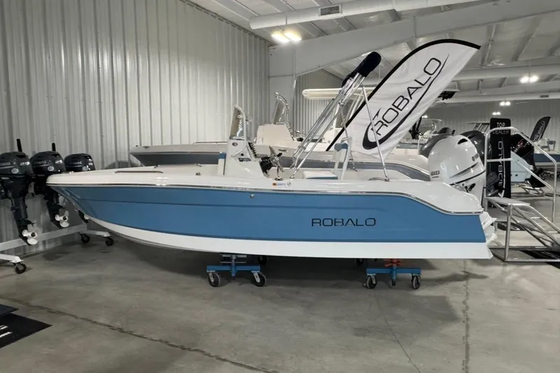 The Image of 2026 Robalo R160 Center Console boat displayed in showroom with blue and white design. - 1