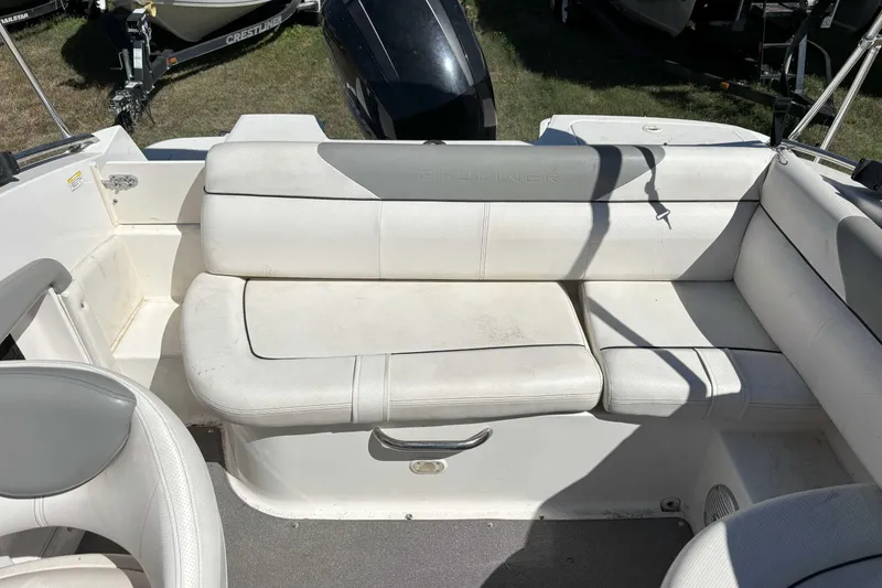 Slide: The Image of 2013 Bayliner 190 Deck Boat interior with white seating and motor in background. - 4
