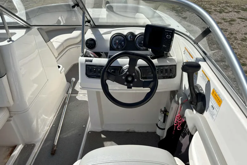 Slide: The Image of 2013 Bayliner 190 Deck Boat cockpit with steering wheel, gauges, and control panel. - 6