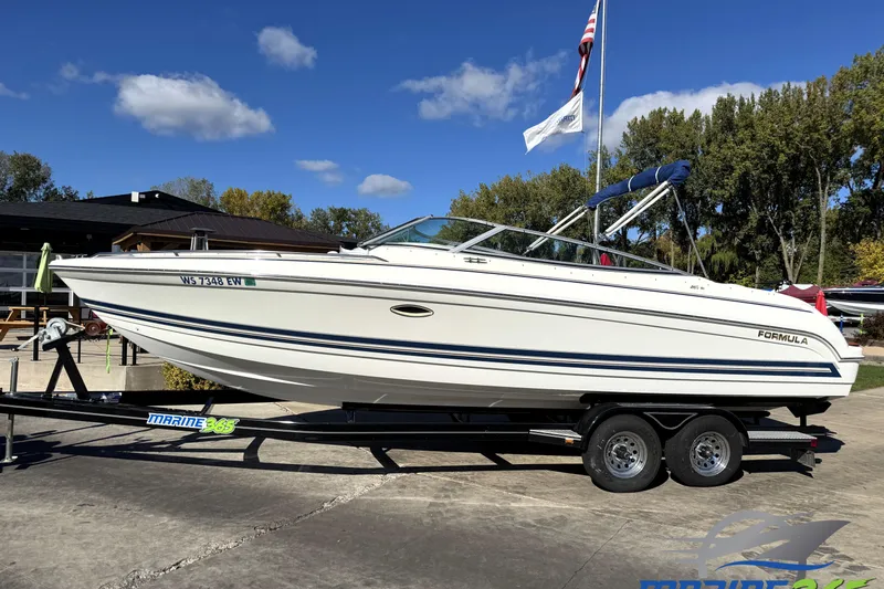 The Image of 2000 Formula 260 Bowrider boat on trailer, parked outdoors under clear blue sky. - 0