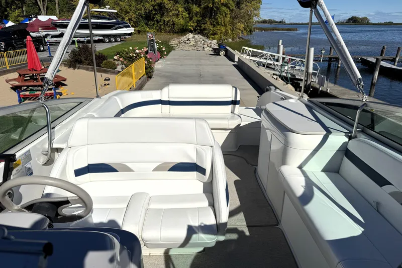 Slide: The Image of 2000 Formula 260 Bowrider boat interior with white seating, docked by a scenic waterfront. - 27