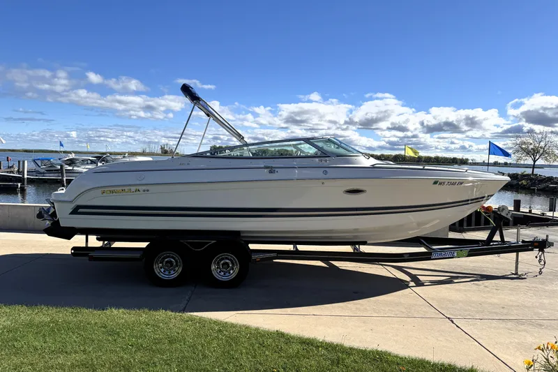 Slide: The Image of 2000 Formula 260 Bowrider boat on trailer by marina under blue sky. - 3