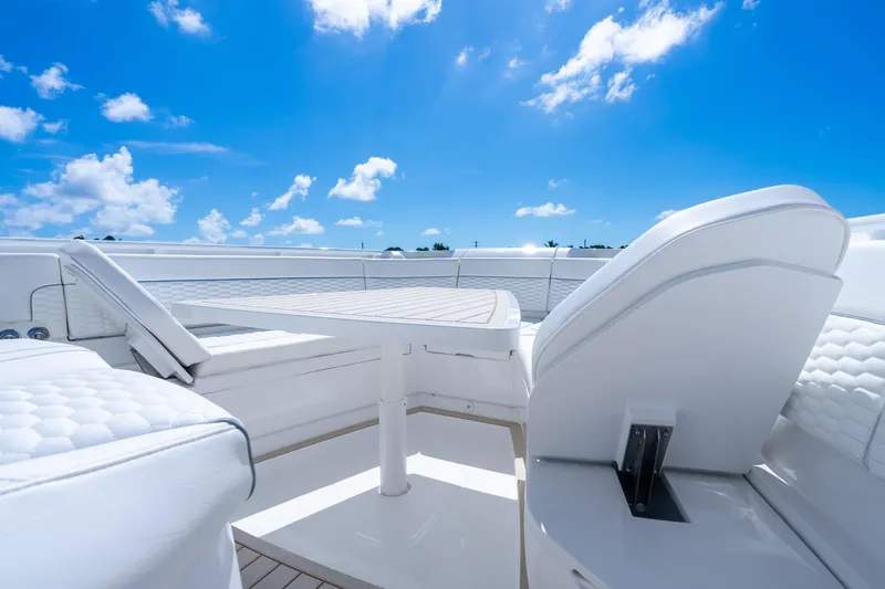 Slide: The Image of 2025 Intrepid 41 Panacea boat interior with white seating and table under blue sky. - 16