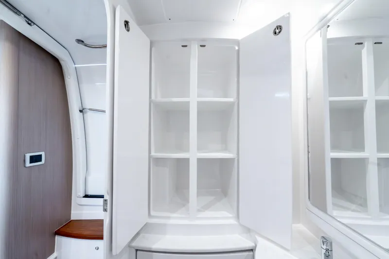 Slide: The Image of Open white cabinet with shelves inside the 2025 Intrepid 41 Panacea boat interior. - 34