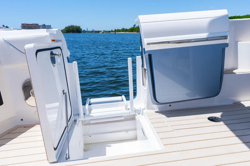 Slide: The Image of 2025 Intrepid 41 Panacea boat deck with open hatch, overlooking serene blue waters. - 61