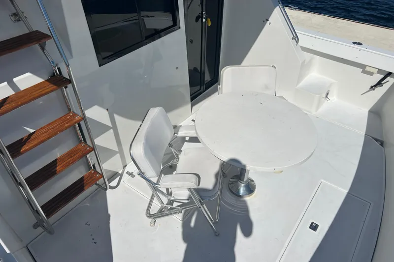 Slide: The Image of 1987 Carver 4227 Cockpit Motor Yacht with white seating and table on deck. - 16