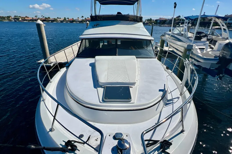 Slide: The Image of 1987 Carver 4227 Cockpit Motor Yacht docked in a marina, sunny day, clear blue water. - 26
