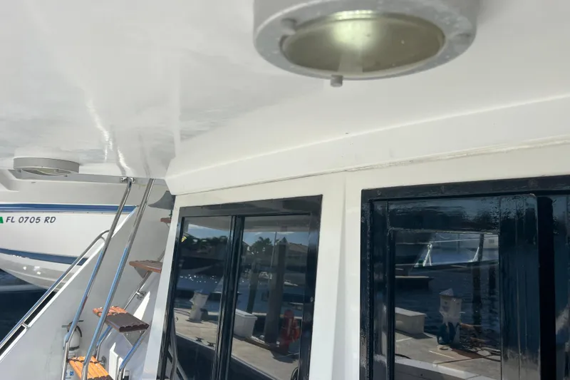 Slide: The Image of 1987 Carver 4227 Cockpit Motor Yacht, exterior view with docked boat in background. - 33