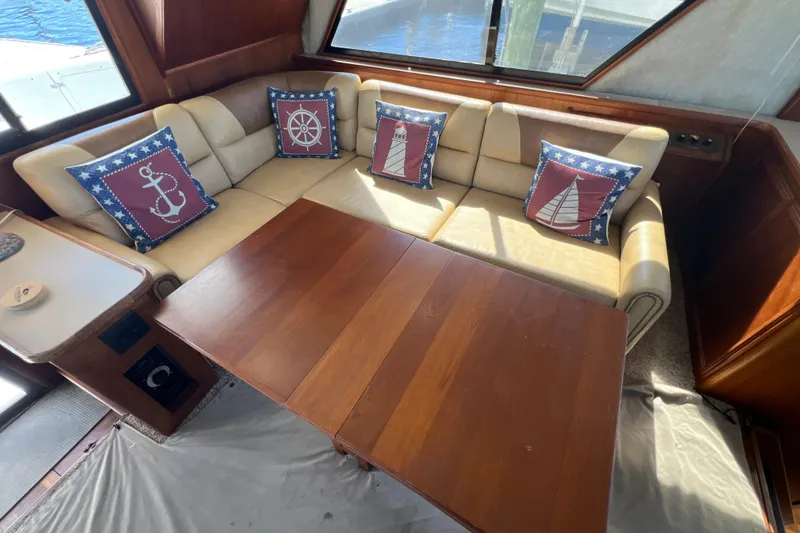Slide: The Image of Interior of 1987 Carver 4227 Cockpit Motor Yacht with nautical-themed cushions and wooden table. - 40