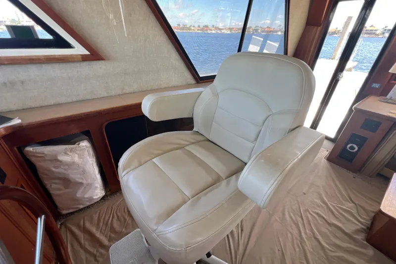 Slide: The Image of 1987 Carver 4227 Cockpit Motor Yacht interior with white captain's chair and scenic water view. - 46