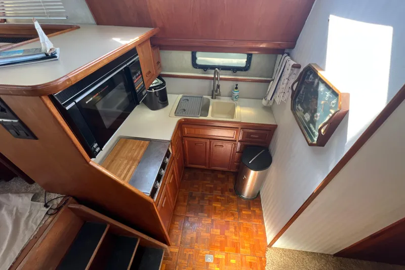 Slide: The Image of 1987 Carver 4227 Cockpit Motor Yacht kitchen with wooden cabinetry and modern appliances. - 53