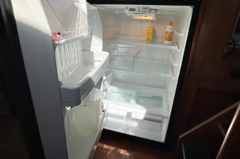 Slide: The Image of Open refrigerator inside 1987 Carver 4227 Cockpit Motor Yacht, containing minimal items. - 59