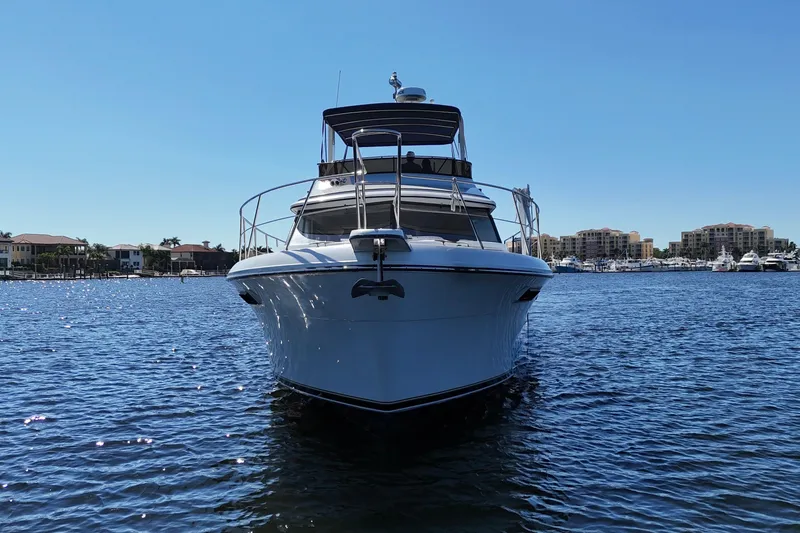 Slide: The Image of 1987 Carver 4227 Cockpit Motor Yacht on calm water, with marina in background. - 6