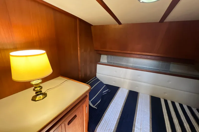 Slide: The Image of Cozy cabin interior of 1987 Carver 4227 Cockpit Motor Yacht with lamp and striped bedding. - 61