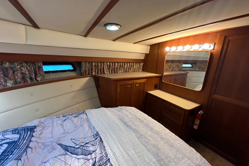 Slide: The Image of 1987 Carver 4227 Cockpit Motor Yacht bedroom with wood cabinetry and nautical bedding. - 67