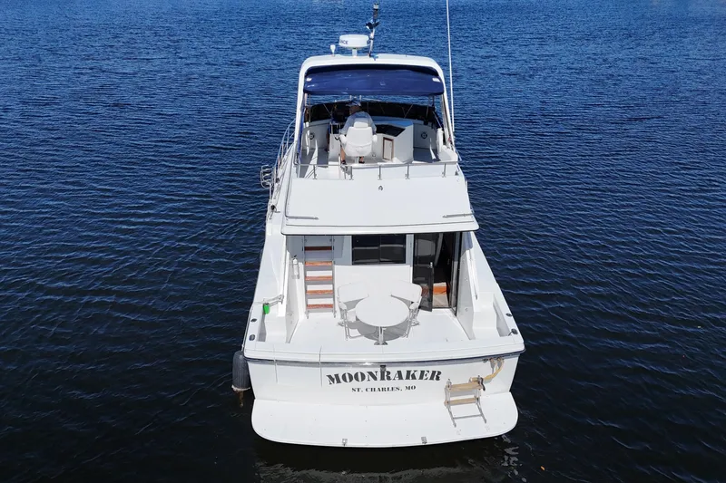 Slide: The Image of 1987 Carver 4227 Cockpit Motor Yacht on water, rear view, named "Moonraker". - 8