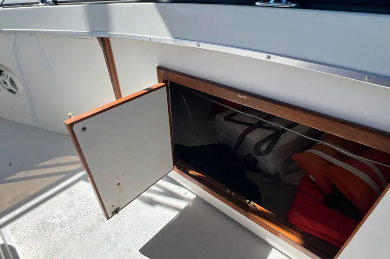 Slide: The Image of 1987 Carver 4227 Cockpit Motor Yacht storage compartment with open door, revealing life jackets. - 83