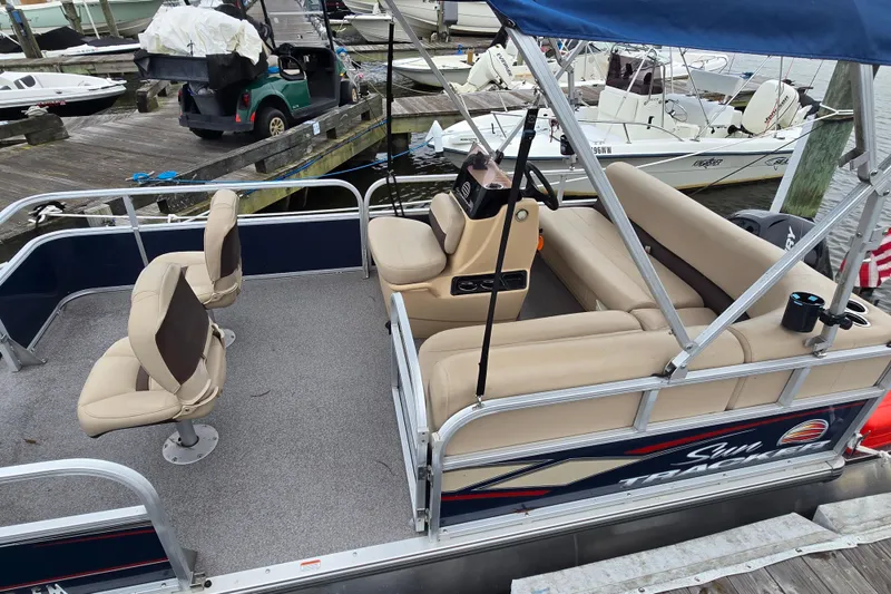 Slide: The Image of 2019 TRACKER MARINE Bass Buggy pontoon boat with beige seating at a marina dock. - 13