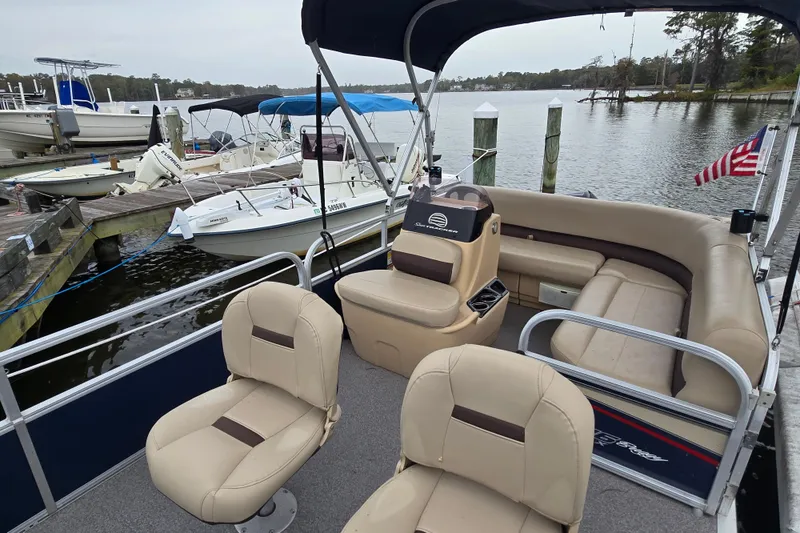 Slide: The Image of 2019 TRACKER MARINE Bass Buggy pontoon boat docked at a marina with seating and canopy. - 16