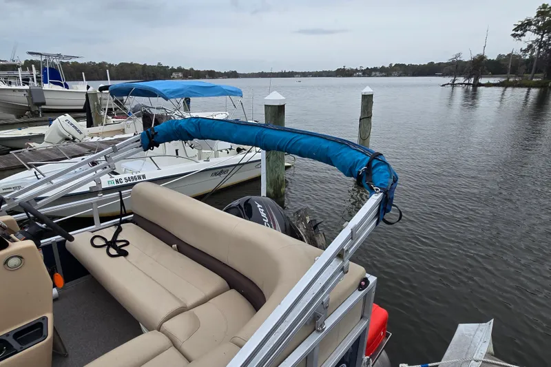 Slide: The Image of 2019 TRACKER MARINE Bass Buggy pontoon boat docked by a serene lake. - 19