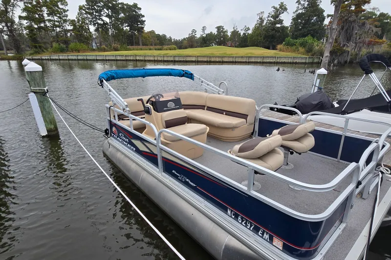 Slide: The Image of 2019 TRACKER MARINE Bass Buggy pontoon boat docked on a serene lake. - 4