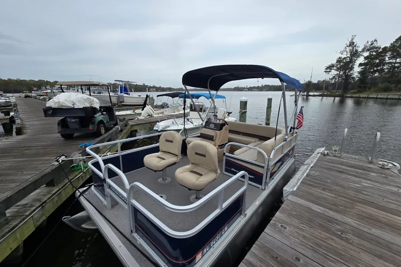 Slide: The Image of 2019 TRACKER MARINE Bass Buggy pontoon boat docked at a marina with scenic water view. - 5