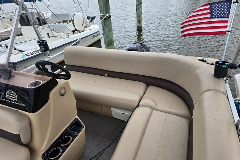 Slide: The Image of 2019 TRACKER MARINE Bass Buggy pontoon boat with American flag, docked by the water. - 9