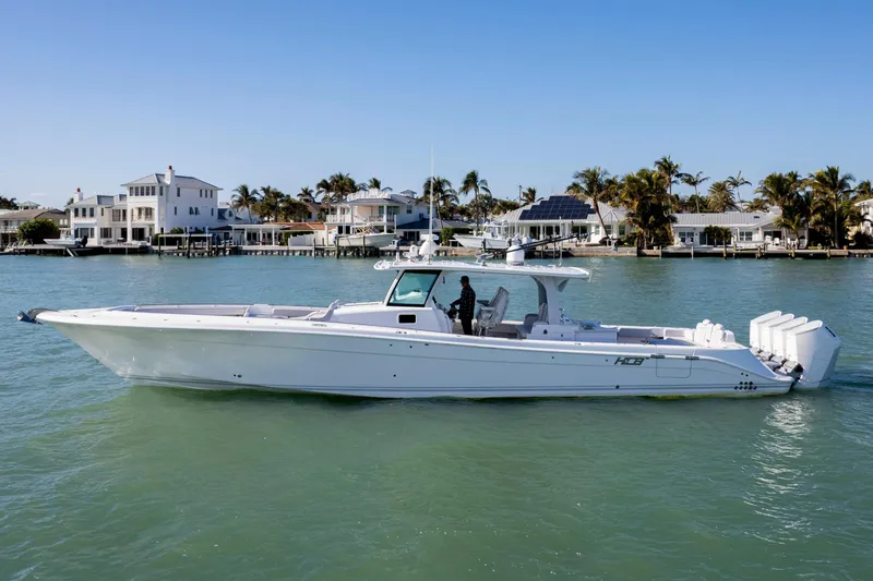 Slide: The Image of 2024 HCB 53 Sueños luxury boat cruising near waterfront homes. - 0