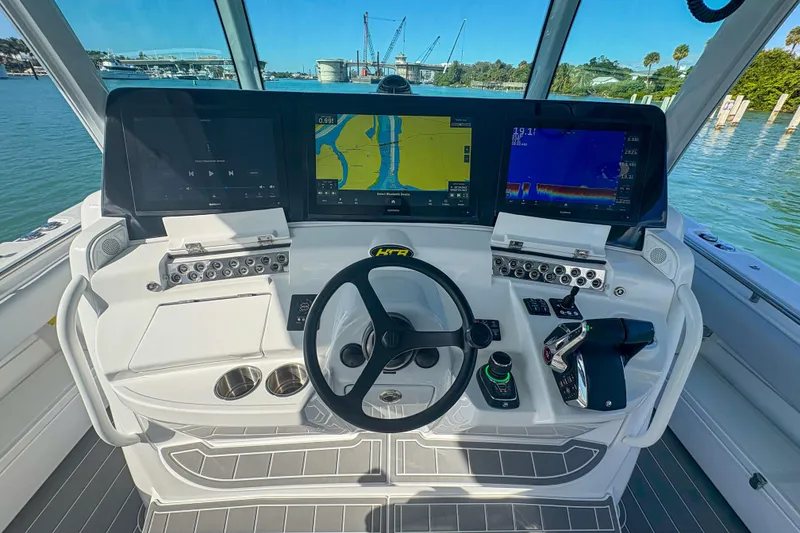 Slide: The Image of 2024 HCB 53 Sueños helm with advanced navigation displays and controls, overlooking a scenic waterfront. - 26