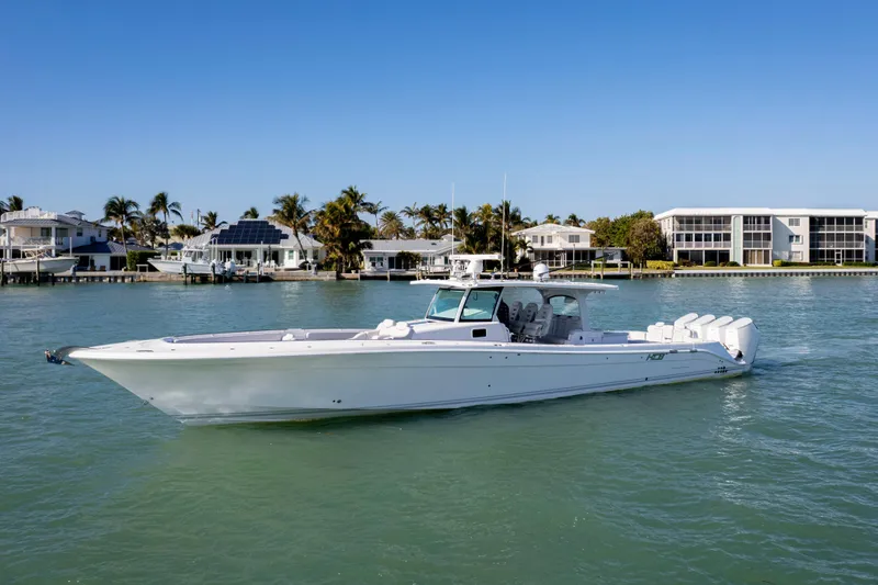 Slide: The Image of 2024 HCB 53 Sueños boat cruising on a sunny day near waterfront homes. - 6