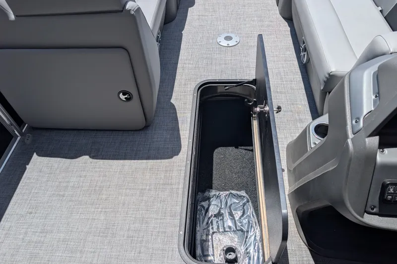 Slide: The Image of 2026 Sun Tracker Party Barge 22 XP3 interior storage compartment with gray seating and flooring. - 90