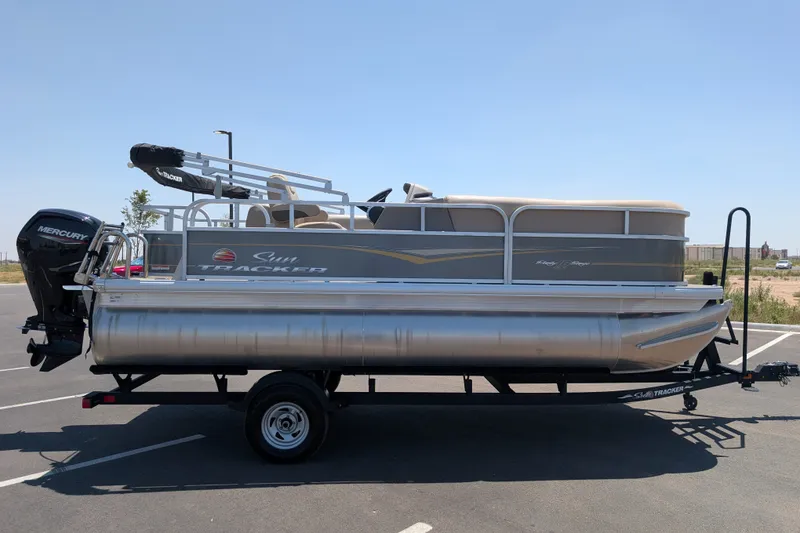 The Image of 2024 Sun Tracker Party Barge 18 DLX pontoon boat on trailer in parking lot. - 0