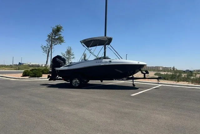 Slide: The Image of 2025 Tahoe T16 boat parked in a sunny lot, featuring a sleek design and canopy. - 3