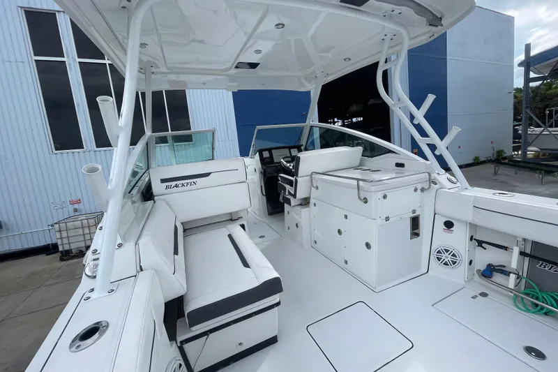 Slide: The Image of 2022 Blackfin 272 DC boat interior with seating and helm, docked near a building. - 13