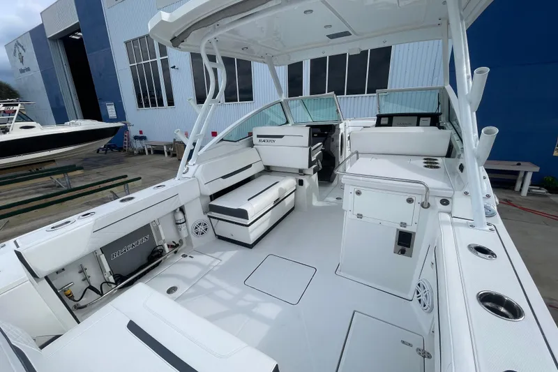 Slide: The Image of 2022 Blackfin 272 DC boat interior with seating and storage, docked near a blue building. - 14
