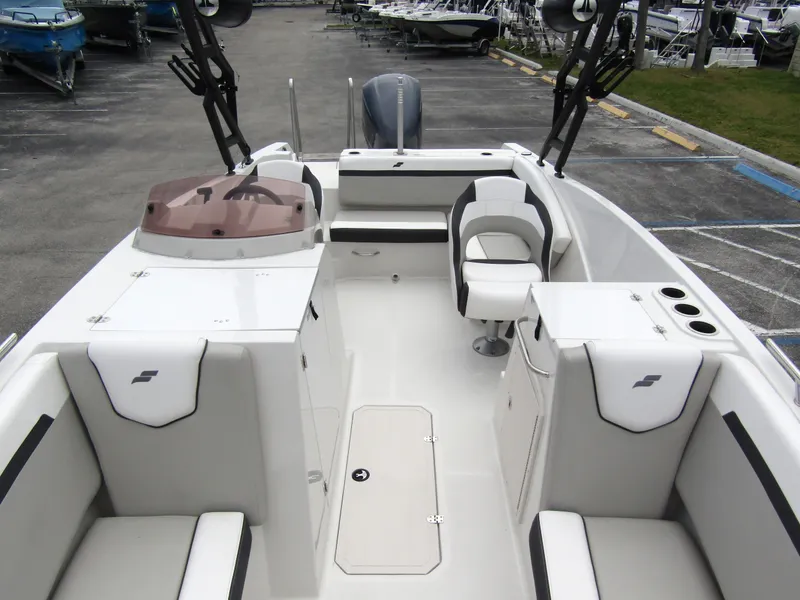 Slide: The Image of 2024 Starcraft SVX 231 OB DH boat interior with seating and helm, docked outdoors. - 9