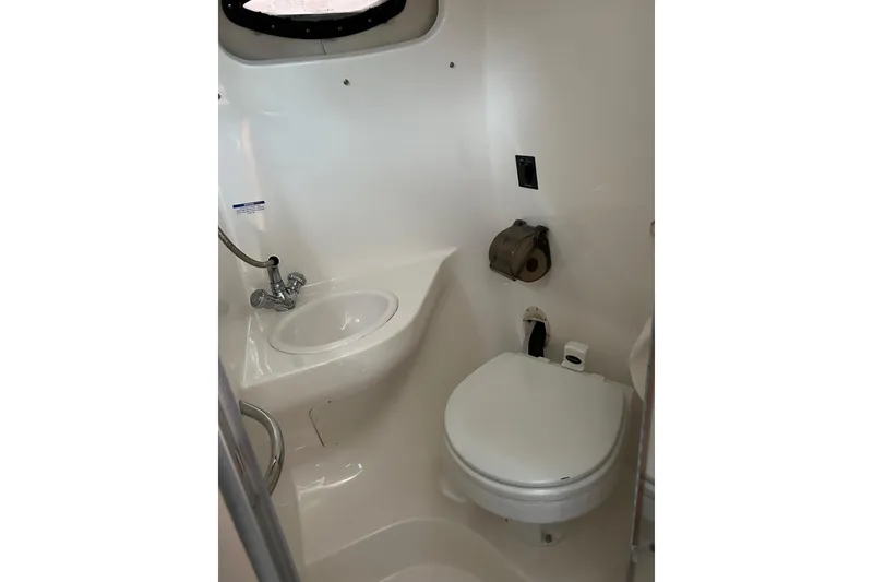 Slide: The Image of 2007 Chaparral Signature 240 boat bathroom with toilet, sink, and porthole. - 10