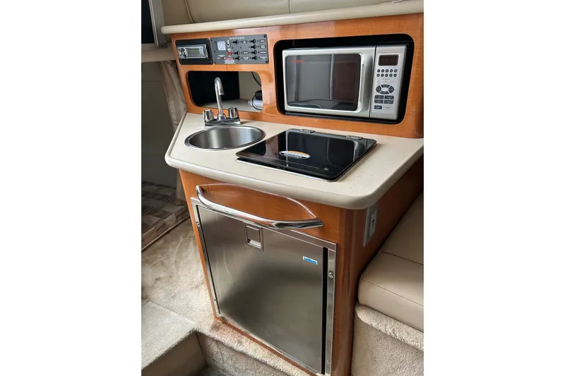 Slide: The Image of 2007 Chaparral Signature 240 boat kitchenette with sink, microwave, stove, and fridge. - 6