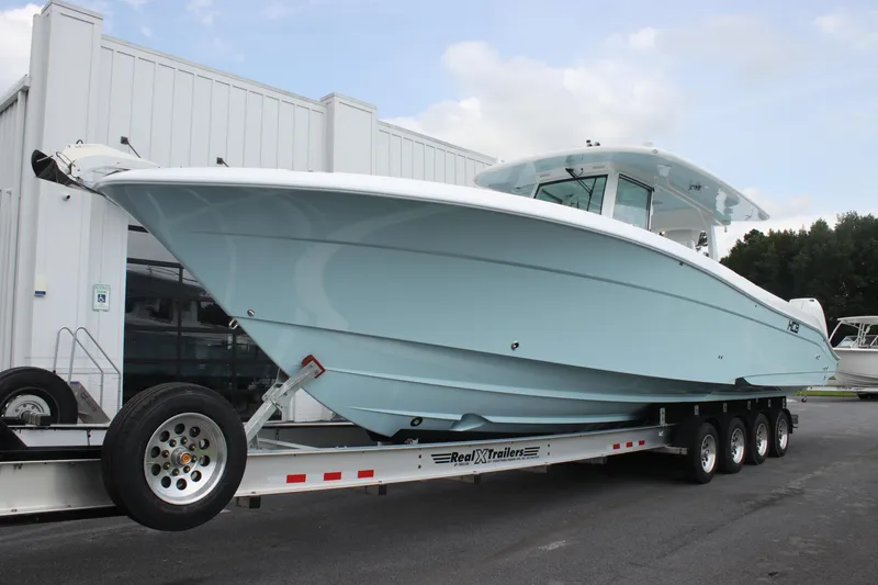 Slide: The Image of 2025 HCB Lujo boat on trailer, light blue hull, parked outside a building. - 6