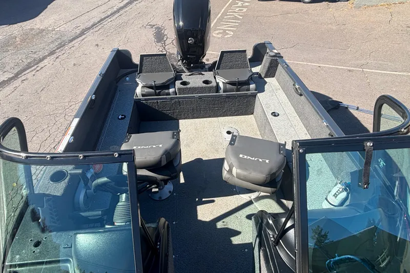 Slide: The Image of 2021 Lund 1650 Rebel XL Sport boat interior with seating and motor, parked on pavement. - 12