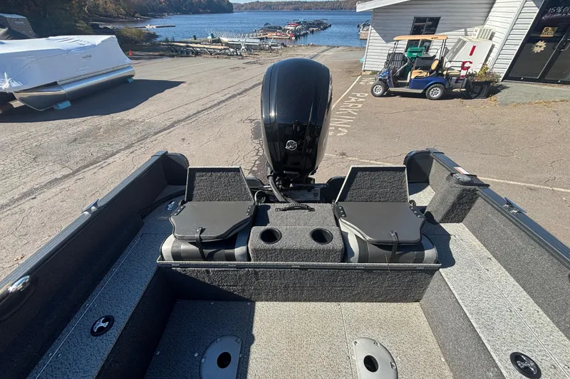 Slide: The Image of 2021 Lund 1650 Rebel XL Sport boat at a lakeside dock, featuring a powerful outboard motor. - 6