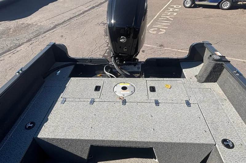 Slide: The Image of 2021 Lund 1650 Rebel XL Sport boat interior with motor, storage compartments, and textured flooring. - 7