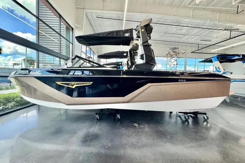 The Image of 2026 Nautique Super Air Nautique S23 boat displayed in a showroom with large windows. - 1